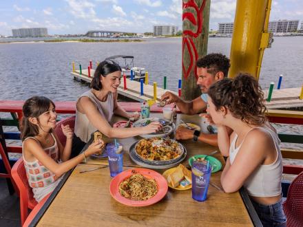Family dining together by the water at Tacky Jacks seafood restaurant in Orange Beach