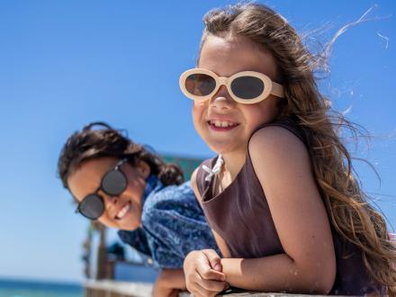 Two young kids with sunglasses smiling at the camera
