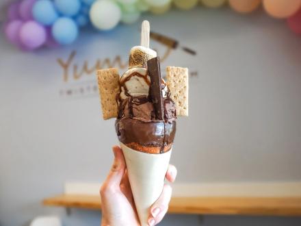 hand holding a s'mores ice cream cone with chocolate, marshmallows, and graham crackers at Yumm Twister Ice Cream