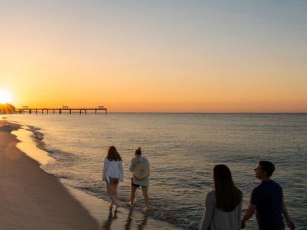 People walking along the shore of the beach at sunrise in Orange Beach