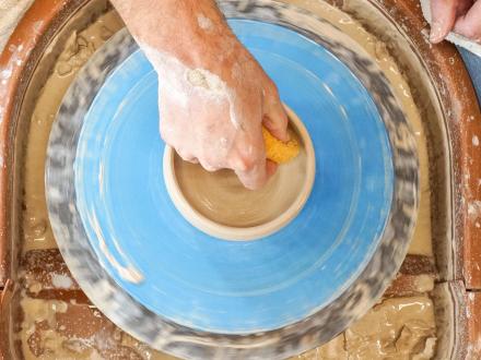 hand creating a pottery bowl on the wheel at The Clay Studio at The Coastal Arts Center