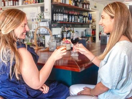 Two women having drinks at the bar at Lauria's Beach Bar, best wine bar in Gulf Shores
