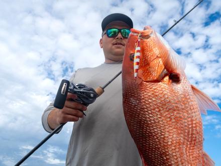 angler holding a large red snapper caught on a charter boat in Gulf Shores