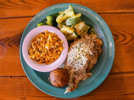a delicious plate of fresh parmesan grouper, sautéed veggies, and rice at Gulf Island Grill beach restaurant in Gulf shores