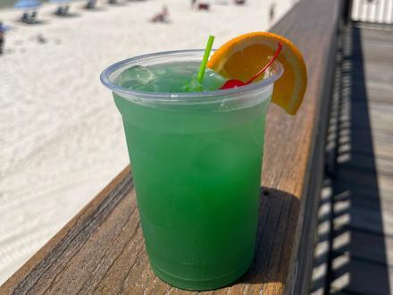 a bright green cocktail sitting on the ledge at Sea-N-Suds beachfront seafood restaurant in Gulf Shores