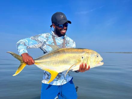 angler holding a jack crevalle caught while inshore fishing on Alabama's Beaches