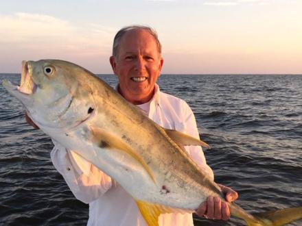 angler holding up a large jack crevalle caught on a fishing charter in Orange Beach