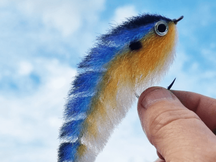 hand holding a bright blue and orange fishing tackle