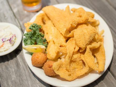 a plate of fried fish, hush puppies, and French fries
