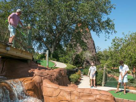 Family playing mini golf at Adventure Island putt putt course in Orange Beach