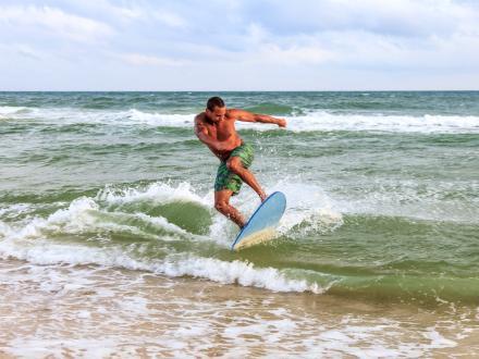 Man riding a skimboard across the surf