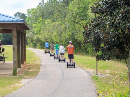 A group of people riding Segways through the trails of Gulf State Park