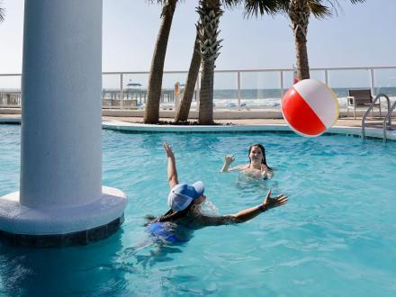 Friends playing with a beach ball in a beachfront pool in Orange Beach