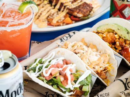 a table full of tacos, fish, a margarita, and a Modelo at Yoho Rum & Tacos restaurant at The Wharf