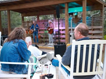 People enjoying live music outside on the deck at Woodside Restaurant in Gulf State Park