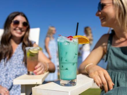 friends with colorful coastal cocktails at Zeke's waterfront restaurant in Orange Beach