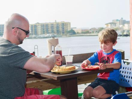 Dad and young son enjoying a waterfront breakfast at Tacky Jacks restaurant in Gulf Shores