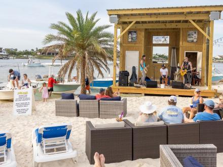Outdoor beach area with couches and live music stage at Flora-Bama Yacht Club waterfront restaurant