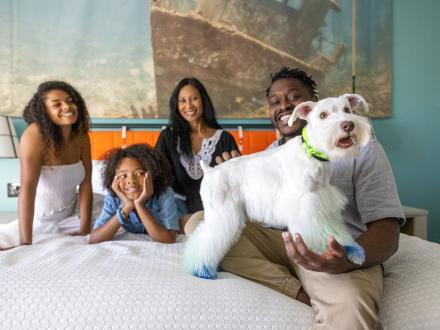 Family holding a dog on a hotel bed in a room at Hotel Indigo in Orange Beach