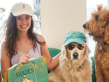 Girl sitting with a dog wearing hats and sunglasses at Shades at The Wharf