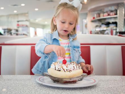Little girl sitting at a booth with a delicious ice cream banana split at Sunliner Diner in Gulf Shores