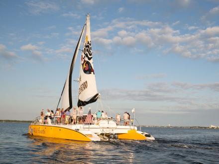 A Sail Wild Hearts sailboat filled with people cruising along the Gulf in Orange Beach
