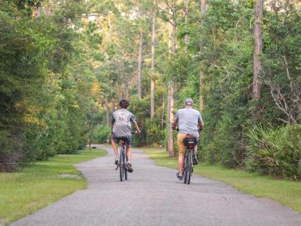 two people biking along the paved trails in Gulf State Park in Orange Beach