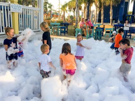 Kids playing in foam during the bubble parties at The Hangout beachfront restaurant