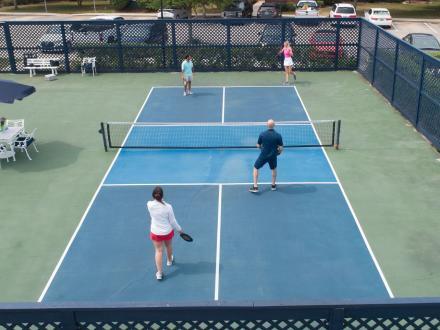 People playing a game of pickleball on the outdoor courts at One Club Gulf Shores