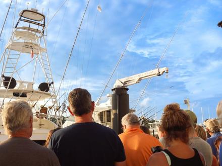 Crowd of people watching boats arrive at The Wharf Marina during a deep-sea fishing tournament