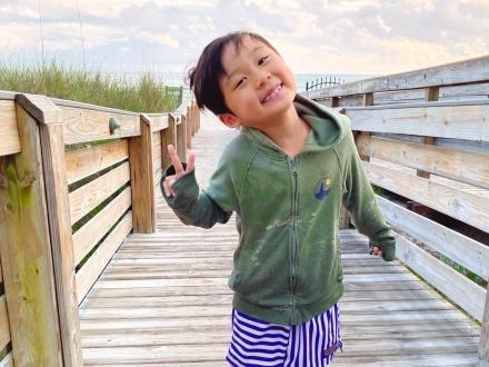 Cute kid smiling on a boardwalk leading to the beach in Gulf Shores