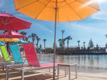 Colorful chairs and umbrellas surrounding the outdoor wave pool at Tropic Falls Waterpark