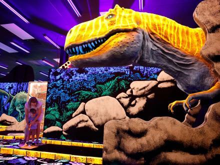 Family playing mini golf at Jurassic Golf indoor, blacklight putt putt