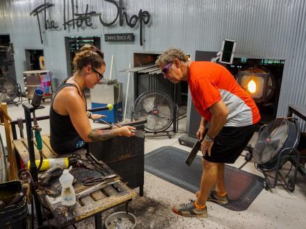 People creating hand blown glass art at The Hot Shop art studio in Orange Beach