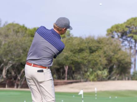 Golfer hitting a ball over the trees on a coastal course in Gulf Shores