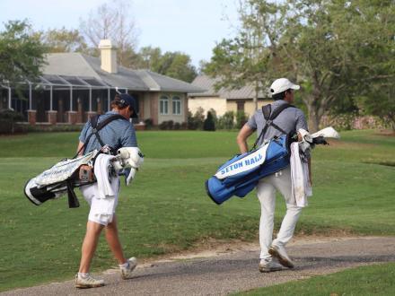 Two golfers carrying golf bags along the course at Craft Farms in Gulf Shores