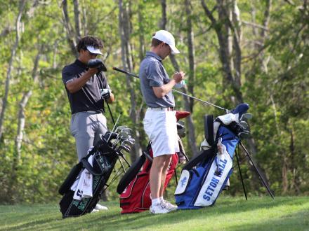 Two golfers picking out clubs from golf bags on the course at Craft Farms