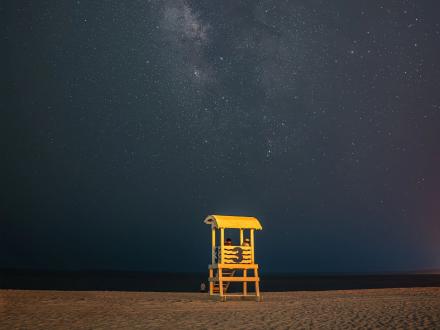 scenic view of the Milky Way over the beach and a lifeguard stand