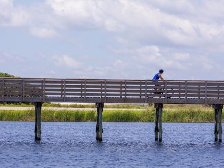 person biking on a boardwalk across Lake Shelby in Gulf State Park