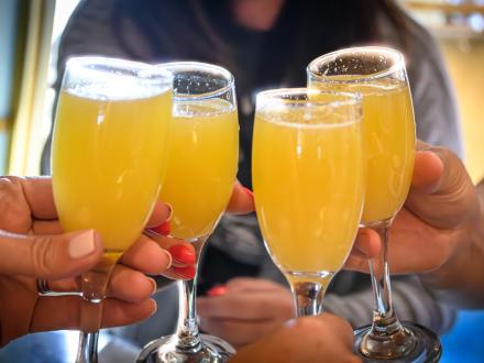 hands cheersing mimosas at brunch