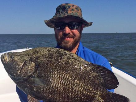 Angler holding up a tripletail caught on a charter in the Gulf in Orange Beach