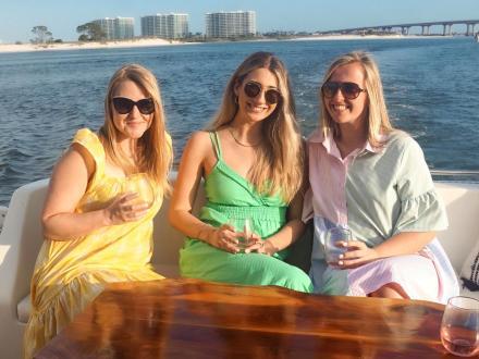 Women enjoying glasses of wine during a sunset cruise through the back bays in Orange Beach