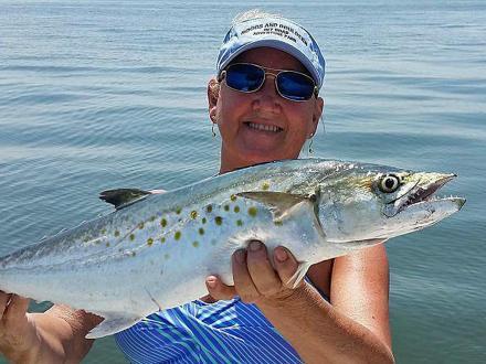 woman holding a mackerel caught while fishing in Orange Beach