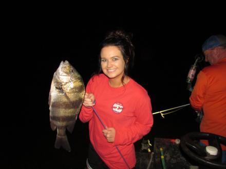 woman holding a fish caught while bow fishing at night
