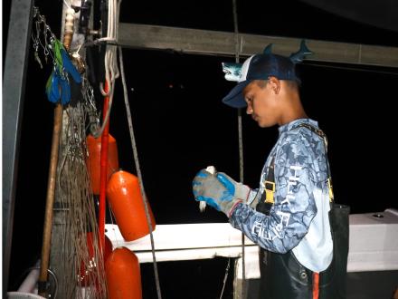 Angler prepping live bait on a nighttime fishing trip in Orange Beach