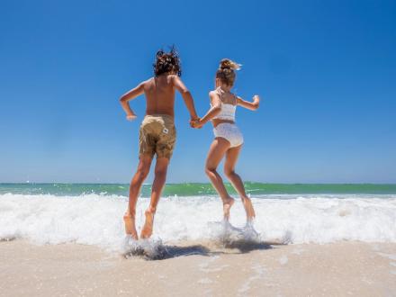 Children jumping over the waves on the beach in Gulf Shores