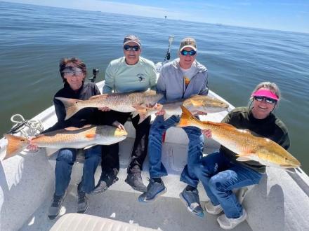 Friends holding up redfish caught on a fishing charter in Orange Beach