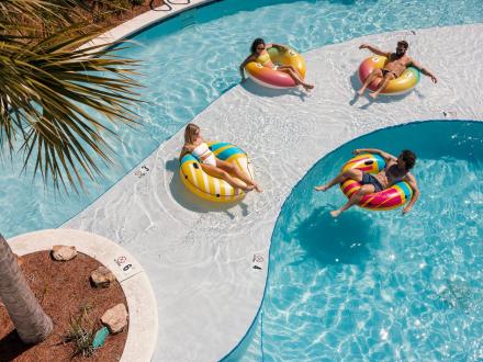 Friends floating in inter tubes along the lazy river at Beach Village Resort vacation home community in Orange Beach