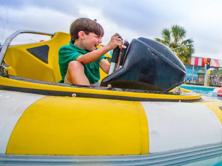 Boy riding the water bumper boats at the track family fun park in gulf shores