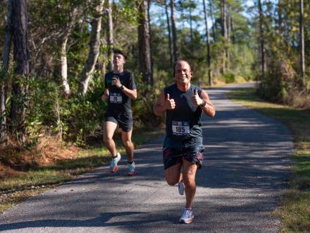 Two runners racing along the trails in Gulf State Park during the Coastal Half Marathon in Orange Beach